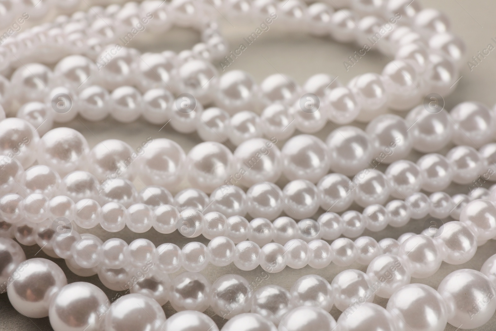 Photo of Elegant pearl necklace on beige background, closeup view