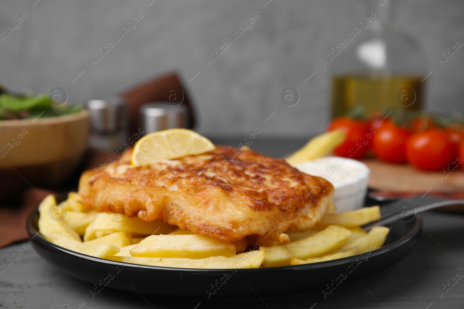 Photo of Tasty soda water battered fish, lemon slice and potato chips on dark wooden table