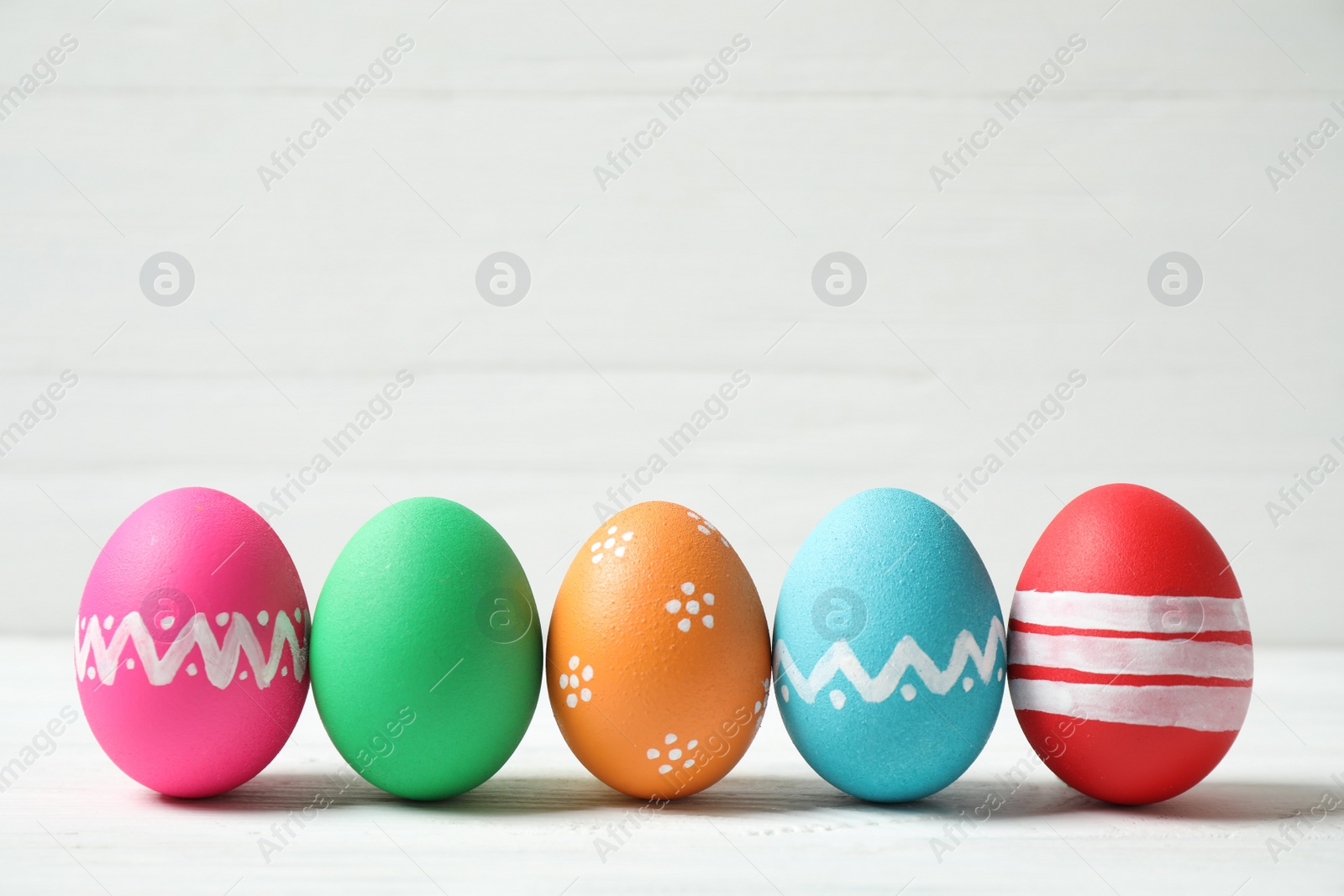 Photo of Colorful Easter eggs on white wooden background. Space for text