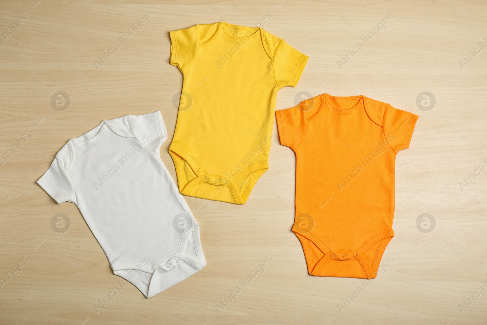 Photo of Different baby bodysuits on wooden background, top view