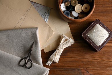 Photo of Set of sewing supplies and accessories with fabric on wooden table, flat lay