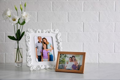 Framed family photos near beautiful bouquet on white table