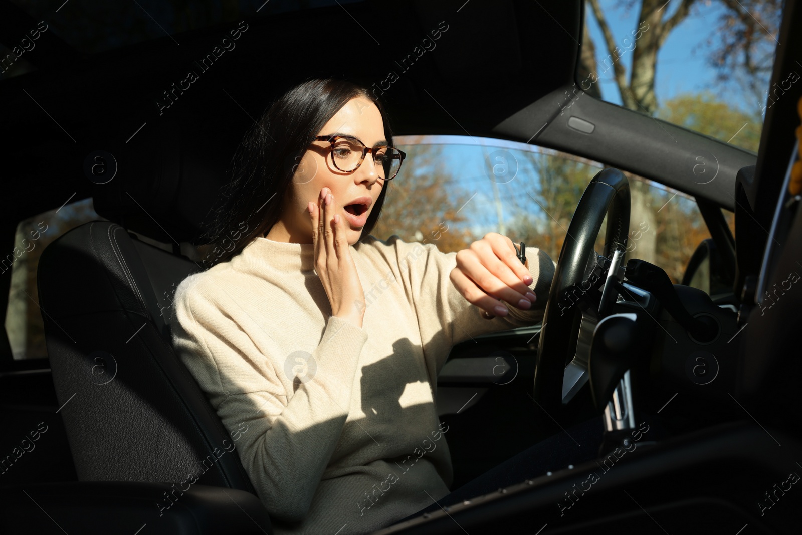 Photo of Emotional woman checking time on watch in car. Being late concept