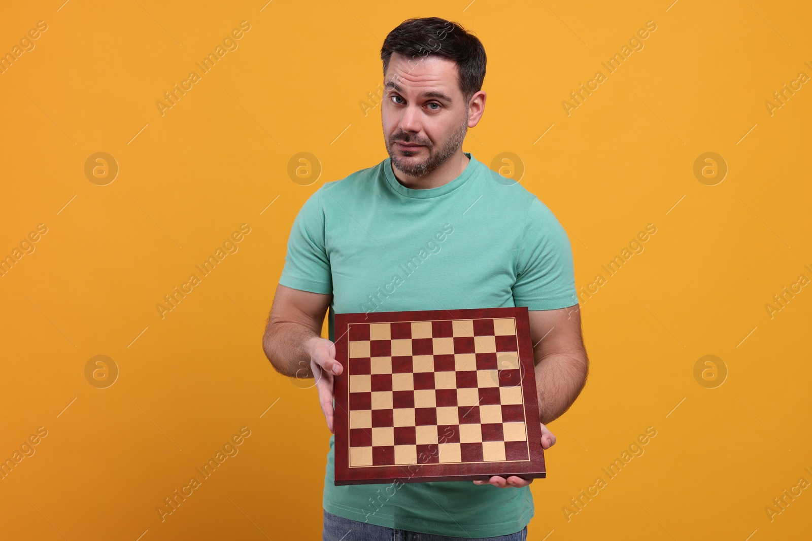 Photo of Adult man holding chessboard on orange background