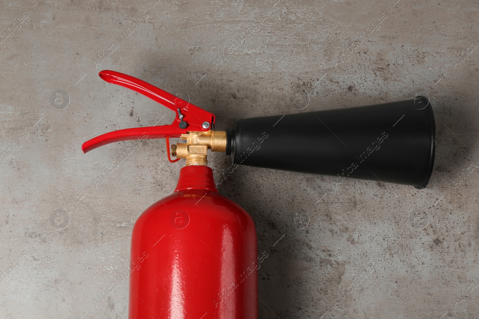 Photo of Fire extinguisher on light grey stone background, top view