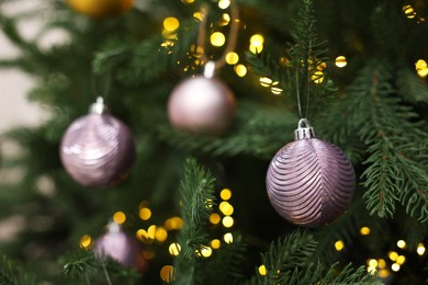 Photo of Beautiful Christmas balls hanging on fir tree, closeup