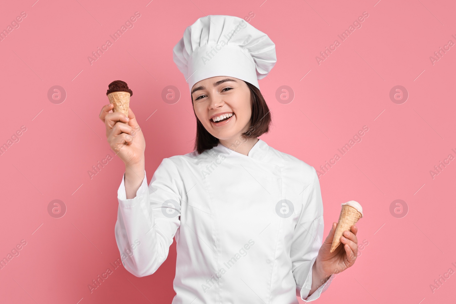 Photo of Happy confectioner with delicious ice cream cones on pink background