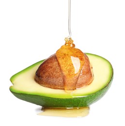 Photo of Pouring essential oil onto cut avocado on white background