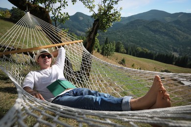 Photo of Young man resting in hammock outdoors on sunny day