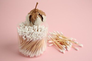 Photo of Container with cotton buds and flower on pink background