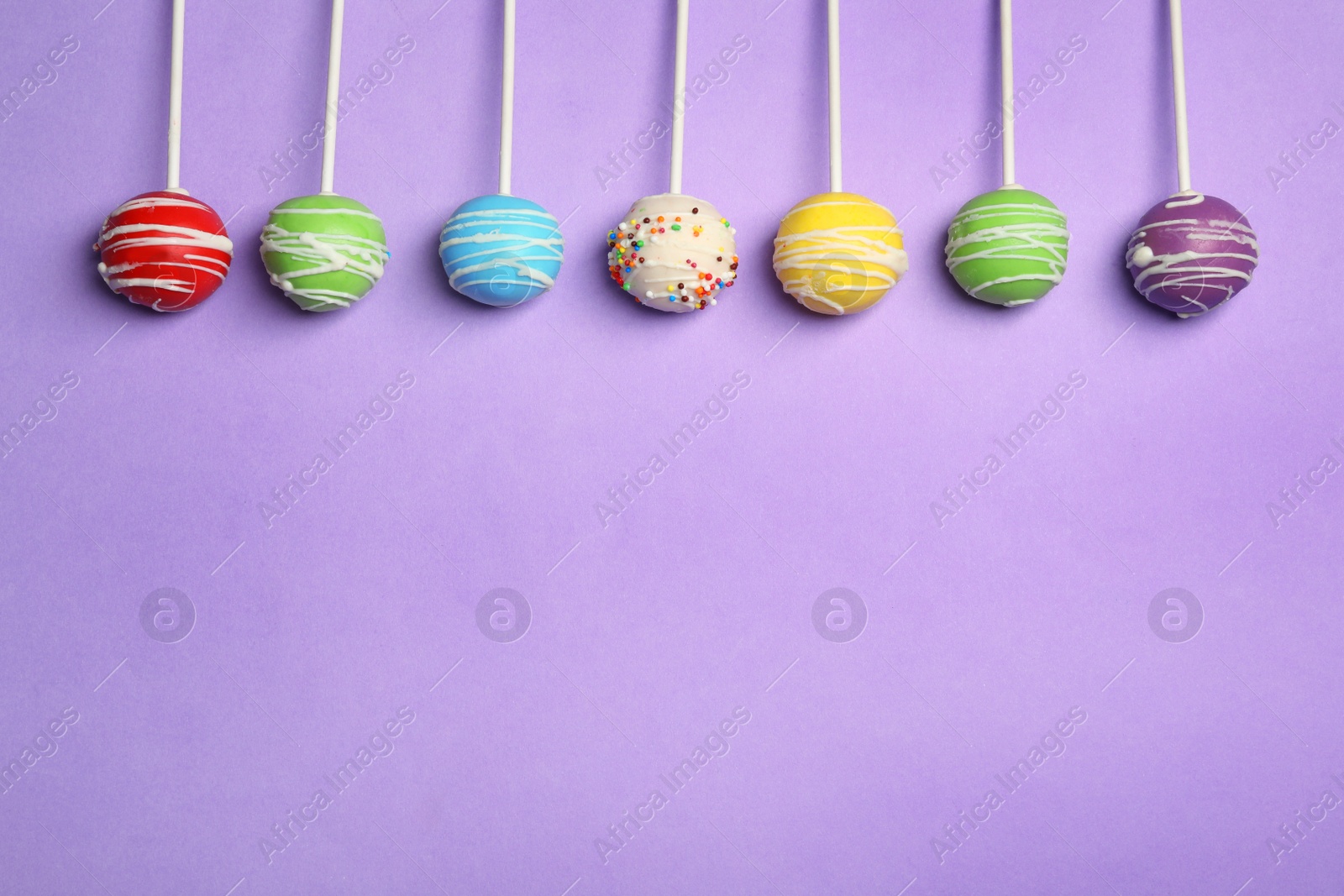 Photo of Bright delicious cake pops on color background, flat lay. Space for text