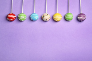 Bright delicious cake pops on color background, flat lay. Space for text