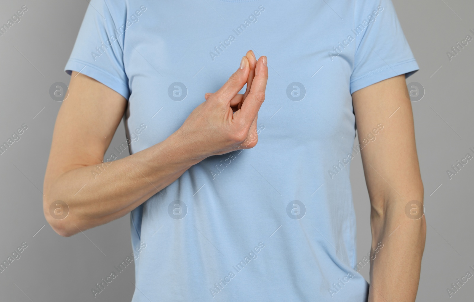 Photo of Woman snapping her fingers on light grey background, closeup. Bad habit