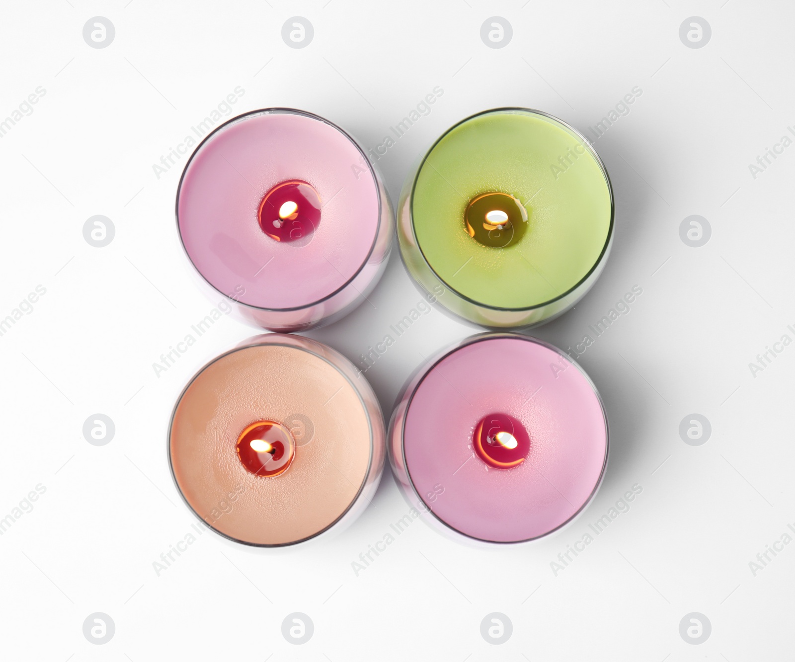 Photo of Color wax candles in glass holders isolated on white, top view