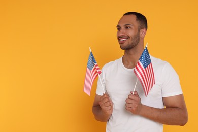 Photo of 4th of July - Independence Day of USA. Happy man with American flags on yellow background, space for text