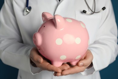 Photo of Doctor holding piggy bank in hands, closeup. Medical insurance