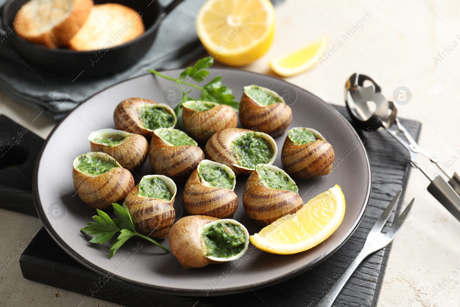 Photo of Delicious cooked snails served on light table