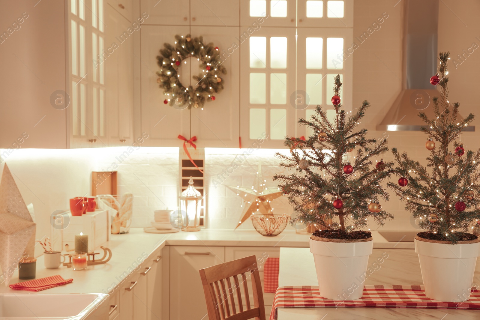 Photo of Small Christmas trees and festive decor in kitchen