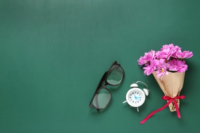 Photo of Flat lay composition with flowers on green chalkboard, space for text. Teacher's day