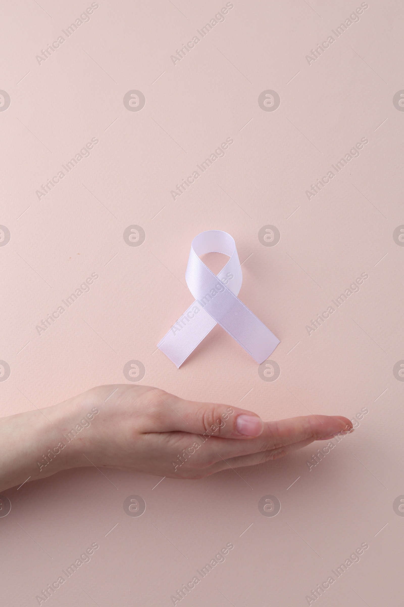 Photo of Woman with white awareness ribbon on beige background, top view