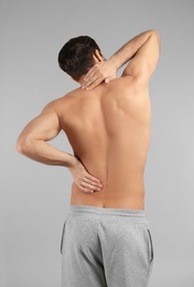 Photo of Young man suffering from back pain on grey background