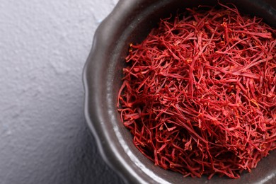 Photo of Aromatic saffron in bowl on gray table, top view