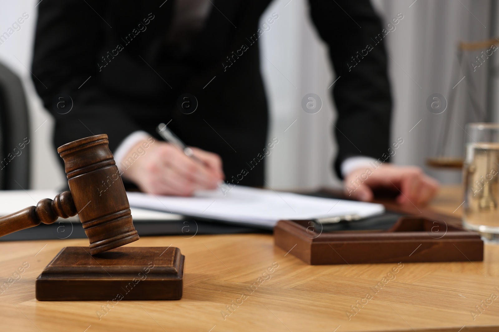 Photo of Lawyer working with documents at wooden table, focus on gavel