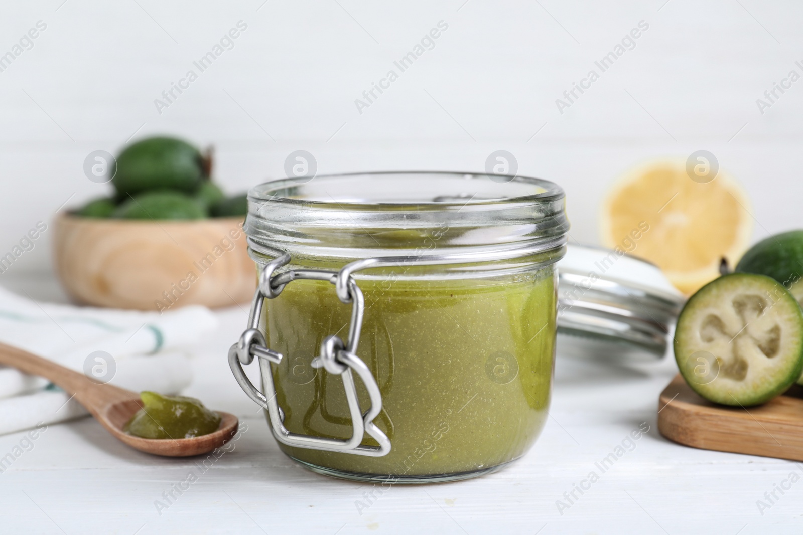 Photo of Feijoa jam in glass jar on white wooden table, closeup