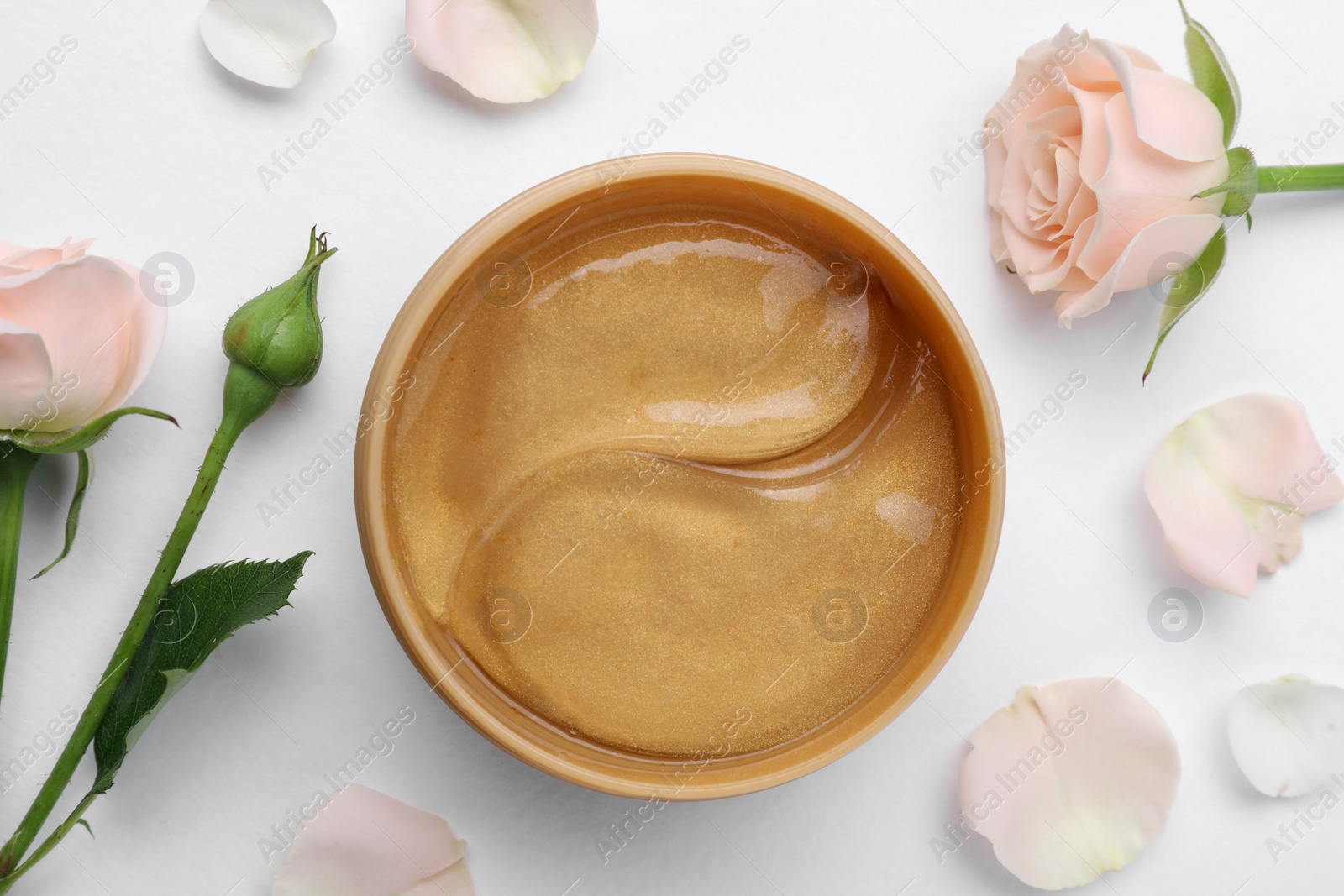 Photo of Under eye patches in jar and rose flowers on white background, flat lay. Cosmetic product