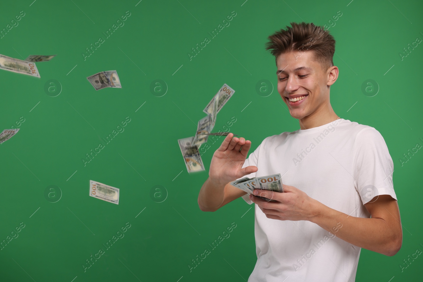 Photo of Happy man throwing dollar banknotes on green background