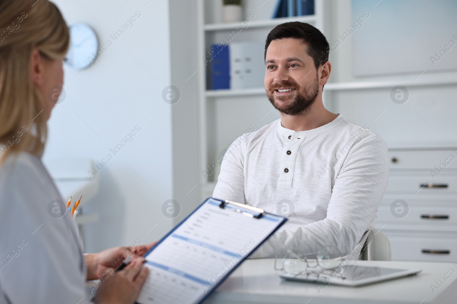 Photo of Professional doctor working with patient at white table in hospital