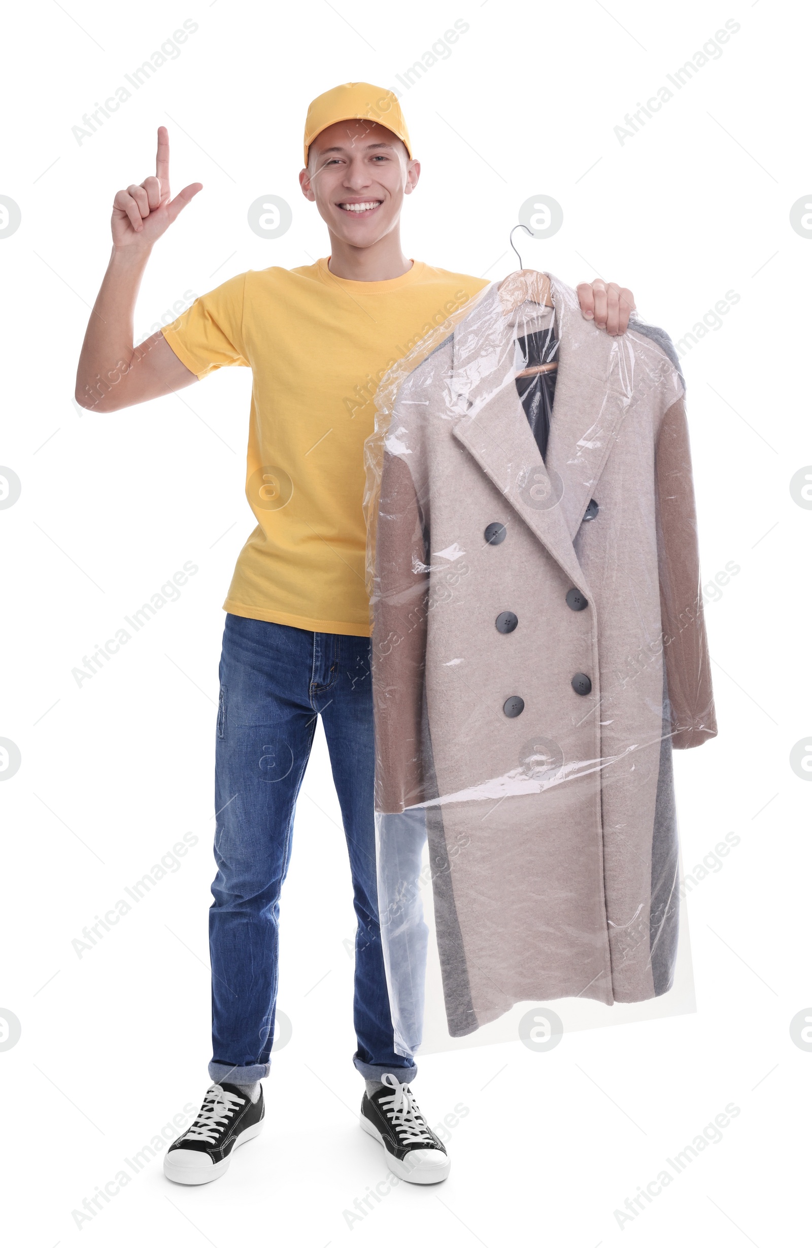 Photo of Dry-cleaning delivery. Happy courier holding coat in plastic bag and pointing at something on white background