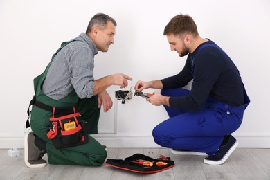 Photo of Senior electrician helping trainee stripping wire ends indoors