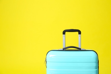 Photo of Stylish blue suitcase on yellow background. Space for text