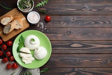 Photo of Delicious burrata cheese with basil served on wooden table, flat lay. Space for text