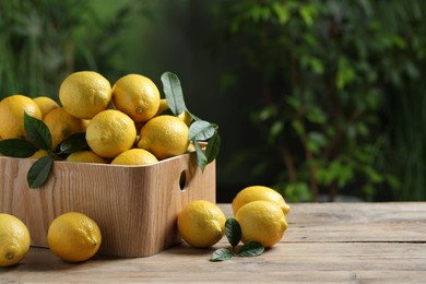 Fresh lemons in crate on wooden table. Space for text