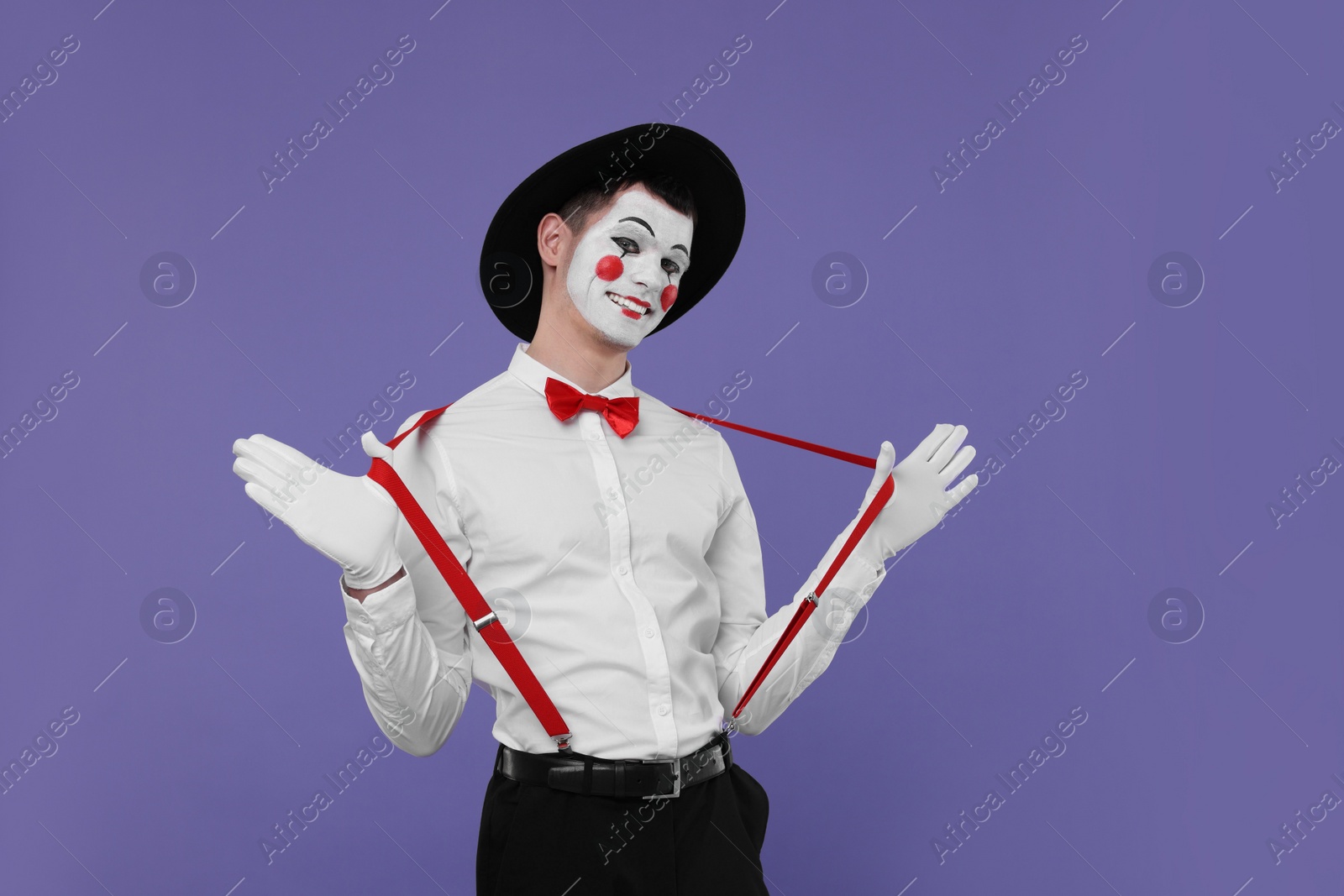 Photo of Funny mime artist in hat posing on purple background