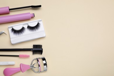 Flat lay composition with fake eyelashes on beige background, space for text