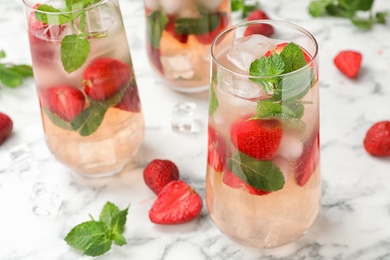 Glasses of refreshing drink with strawberry and mint on marble table, space for text