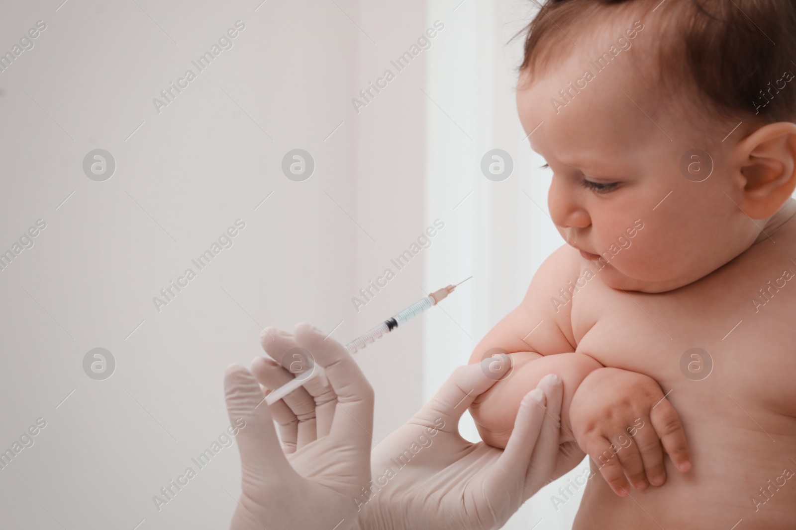 Photo of Doctor vaccinating baby against light background. Health care