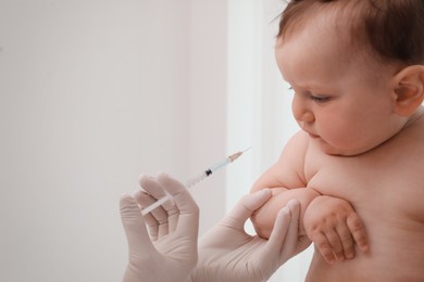 Doctor vaccinating baby against light background. Health care