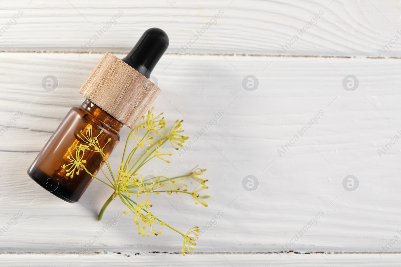 Photo of Bottle of essential oil and fresh dill on white wooden table, flat lay. Space for text