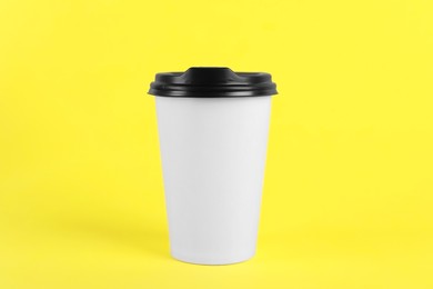 Photo of Paper cup with plastic lid on yellow background. Coffee to go