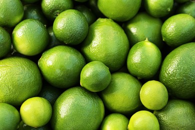 Photo of Fresh ripe green limes as background, top view