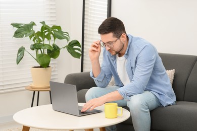 Man working with laptop at table in living room