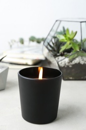 Burning candle and plants on white table, space for text