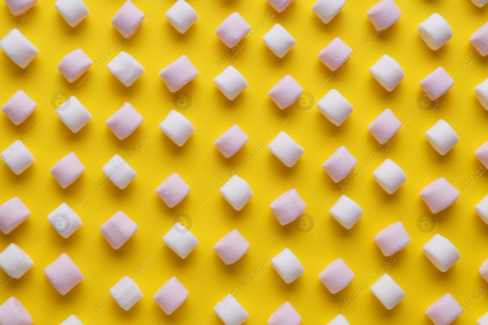 Photo of Delicious puffy marshmallows on yellow background, flat lay