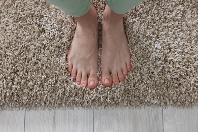 Woman standing on soft light brown carpet at home, top view