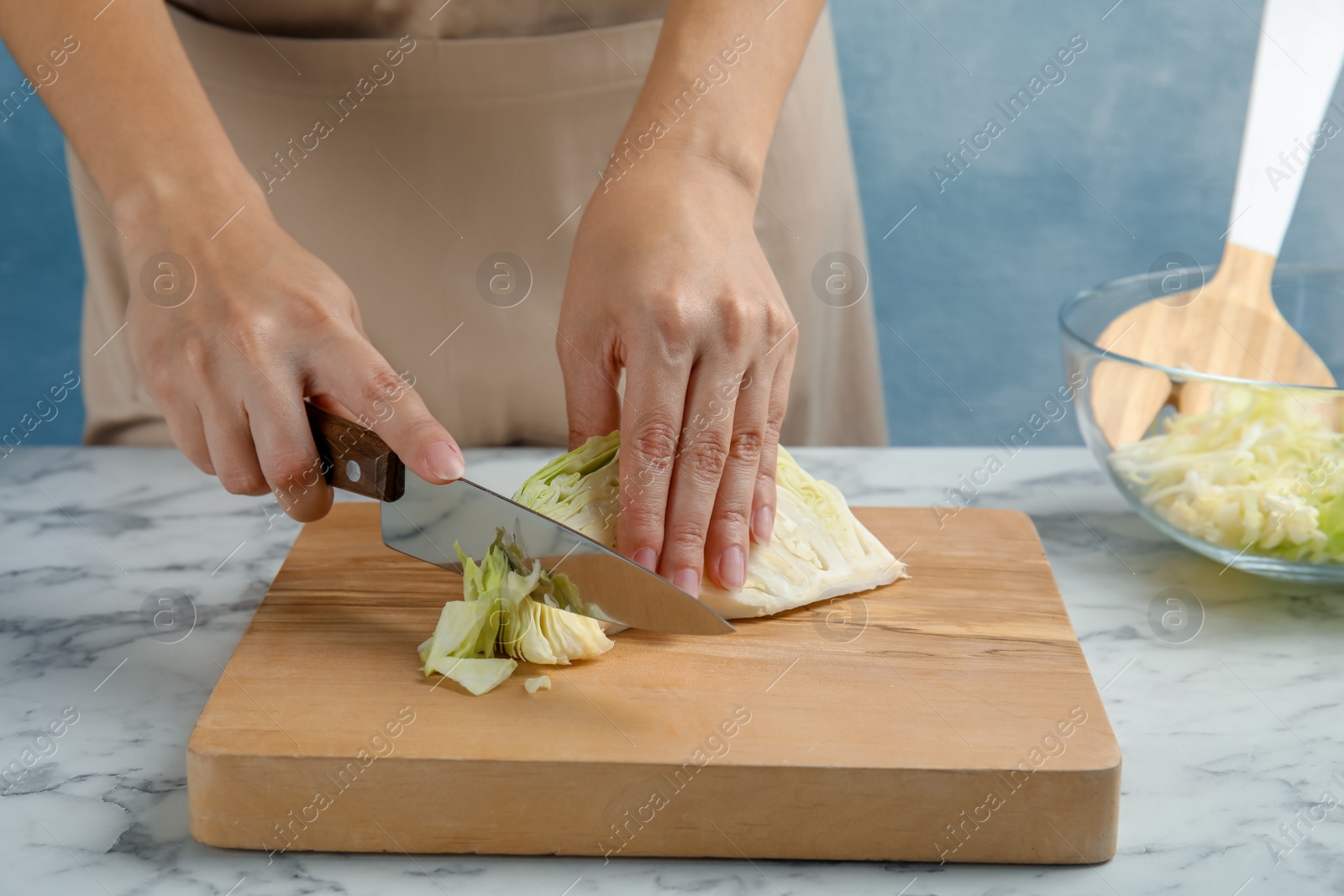 Photo of Woman cutting ripe cabbage at table, closeup