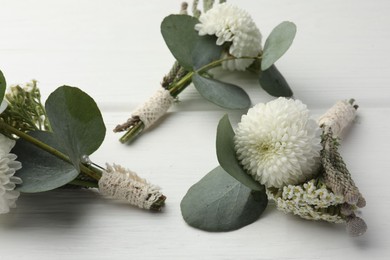 Photo of Small stylish boutonnieres on white wooden table